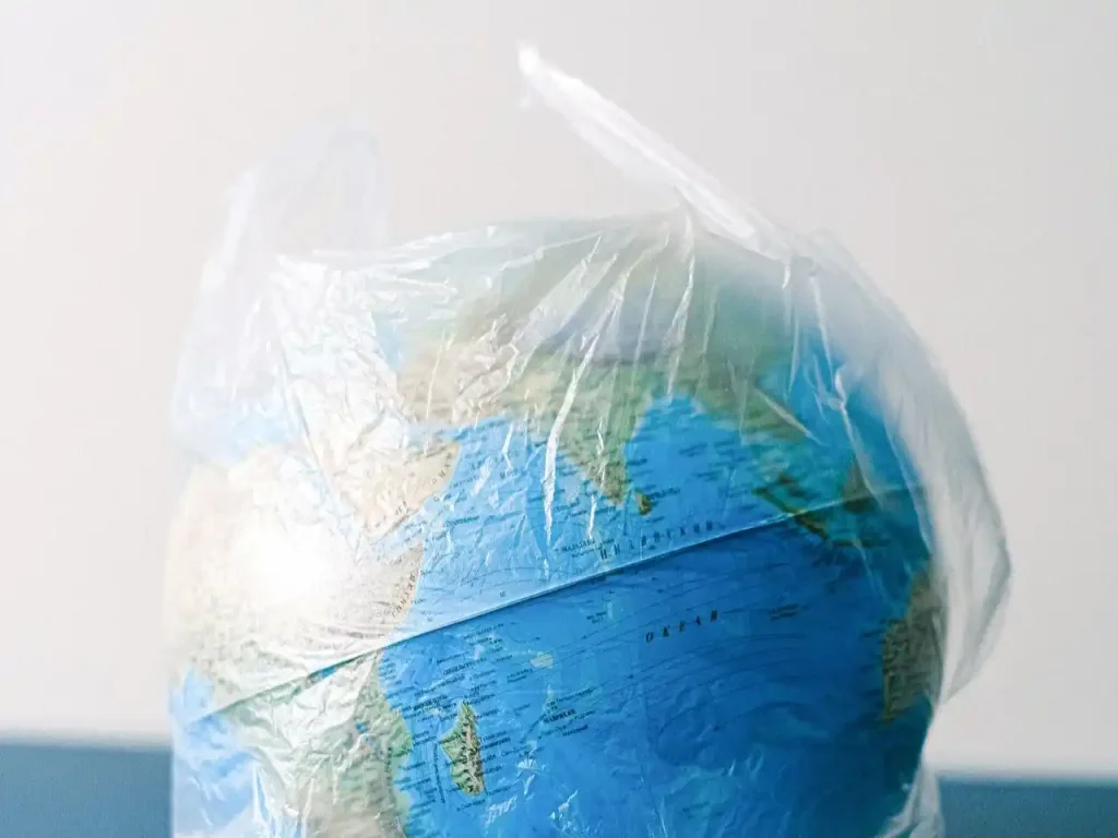 Gambar: Sebuah globe yang terbungkus dalam kantong plastik melambangkan isu lingkungan. Foto oleh Shvetsa